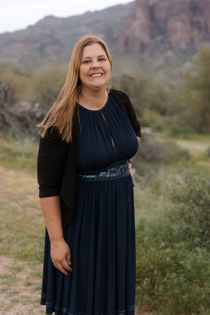Deanne Welsh in a navy dress with the Arizona desert landscape behind her